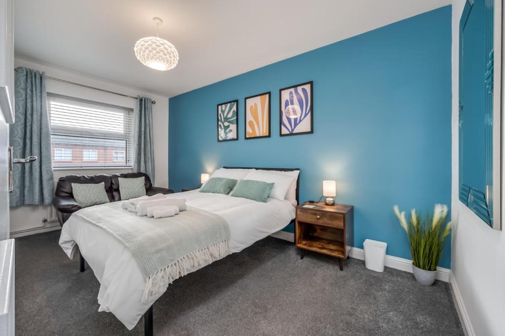 een slaapkamer met een groot bed en een blauwe muur bij Belfast City Centre & allocated Parking by StayByNumbers in Belfast