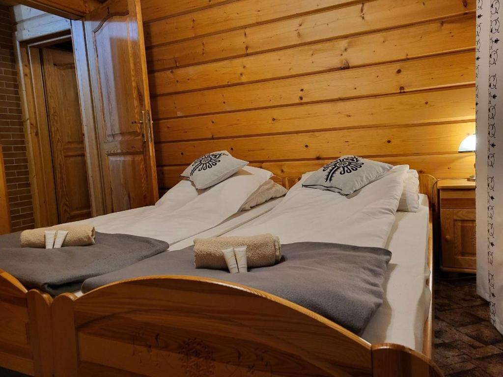 2 łóżka w pokoju z drewnianą ścianą w obiekcie Apartament Harenda w Zakopanem