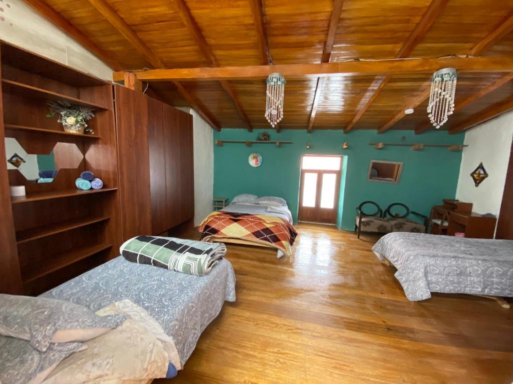 3 camas en una habitación con paredes verdes y techos de madera en Amplia y Céntrica Habitación - H. El Casero, en Cajamarca