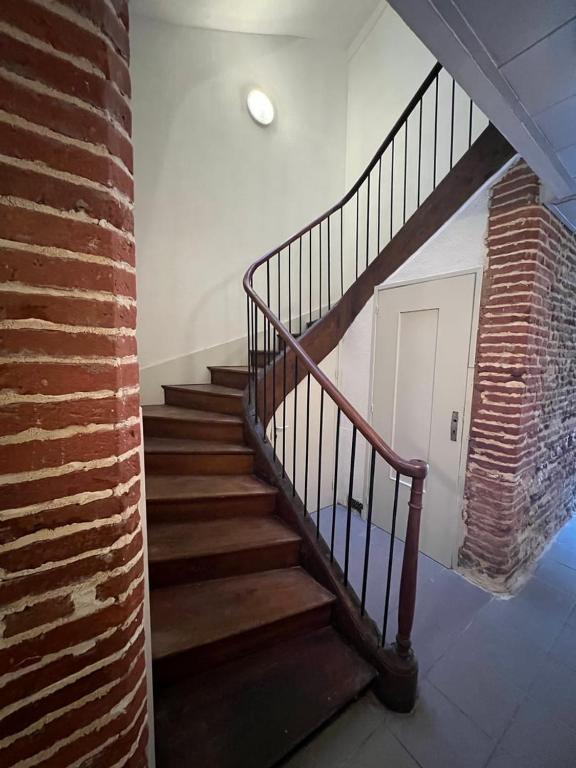 a staircase in a room with a brick wall at Magnifique T2 - proche hyper centre in Toulouse