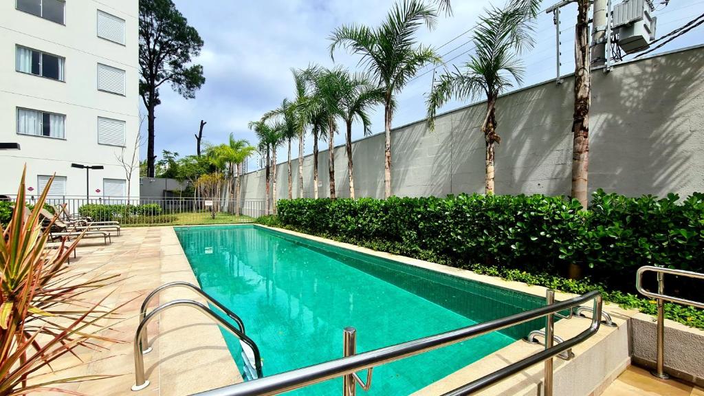 a swimming pool with palm trees next to a building at Aconchegante Apartamento no coração de Santo Amaro in Sao Paulo