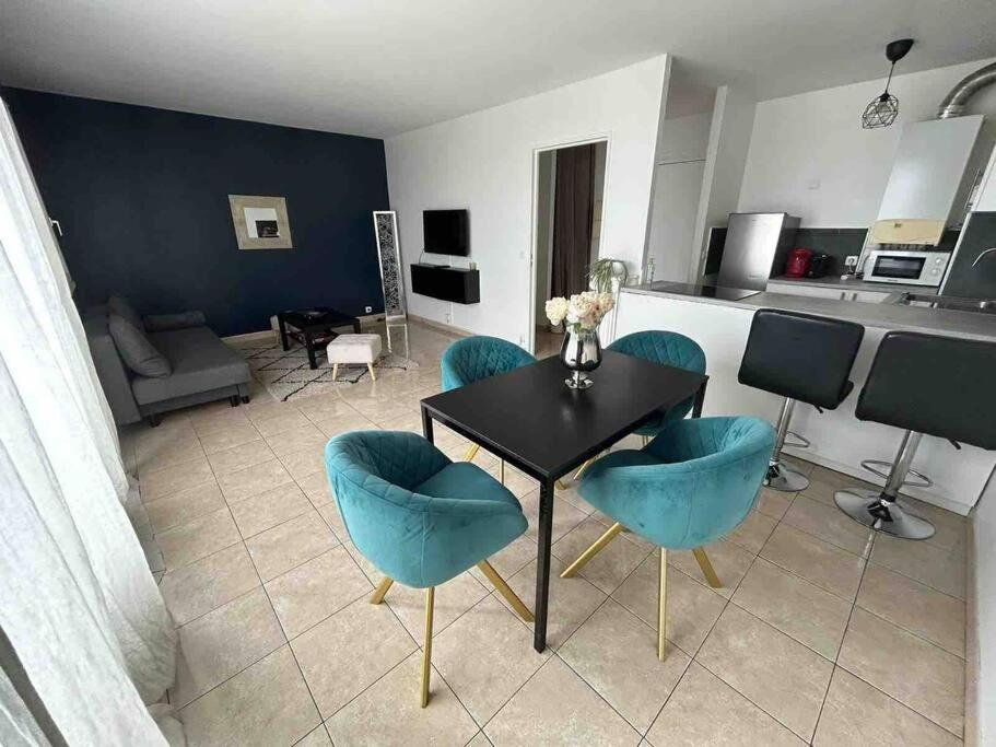 sala de estar con mesa negra y sillas azules en Appartement chaleureux à proximité de Paris, en Saint-Michel-sur-Orge