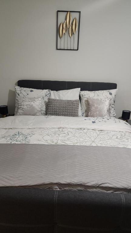 um quarto com uma cama grande com lençóis brancos e almofadas em Studio meublé em Genebra