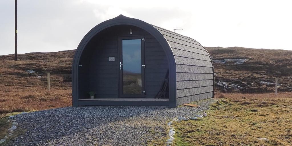 un piccolo edificio con una porta su una collina di Grimsay Glamping, North Uist - Pod Glas a Rossinish