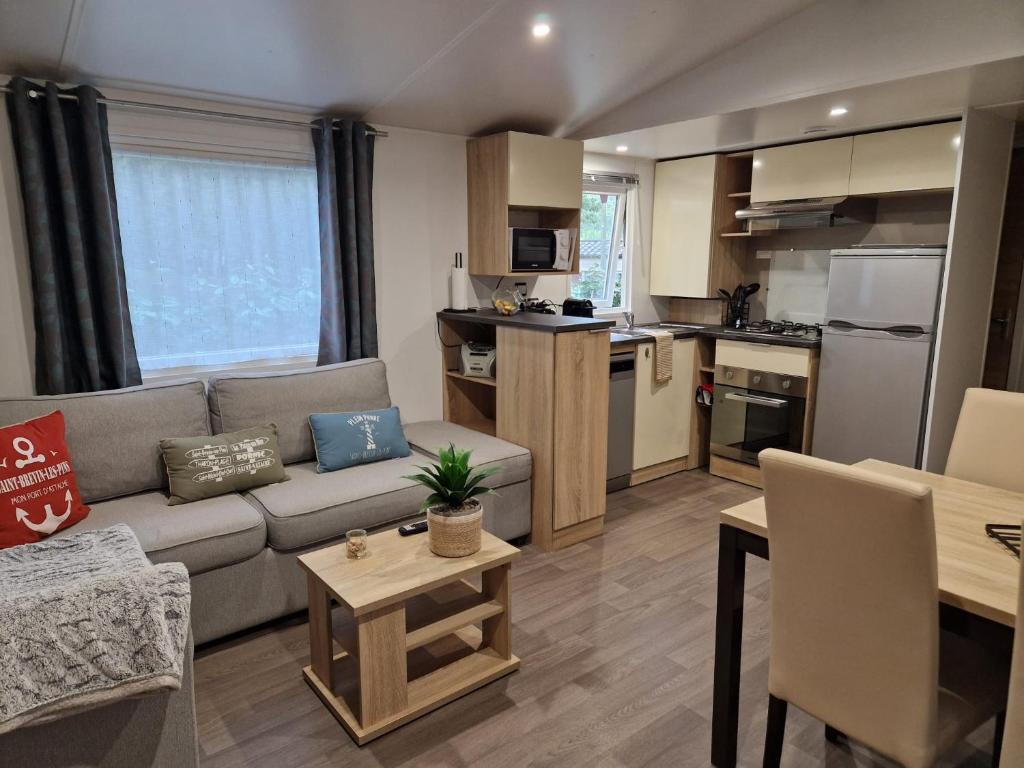 sala de estar con sofá y cocina en Mobil home tout confort 3 chambres camping Les Pierres Couchées en Saint-Brevin-les-Pins