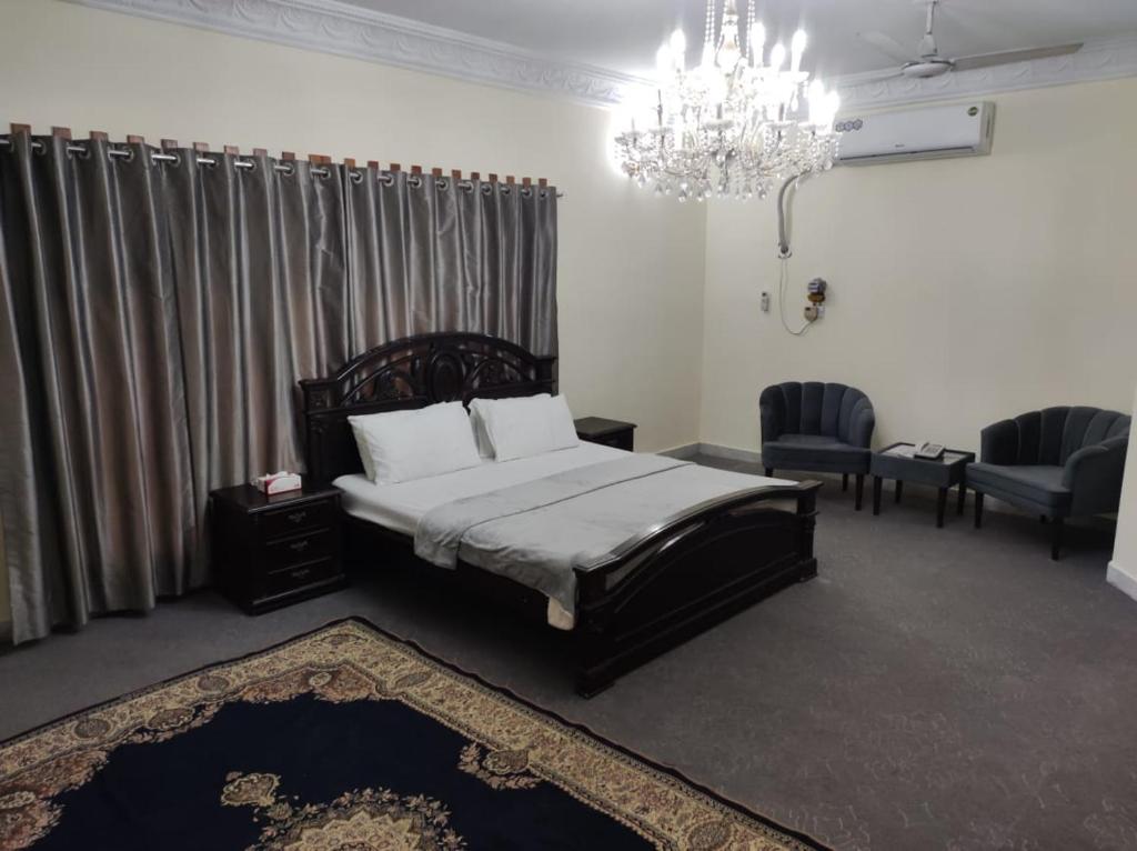 1 dormitorio con cama y lámpara de araña en Askari Gold Crest en Peshawar
