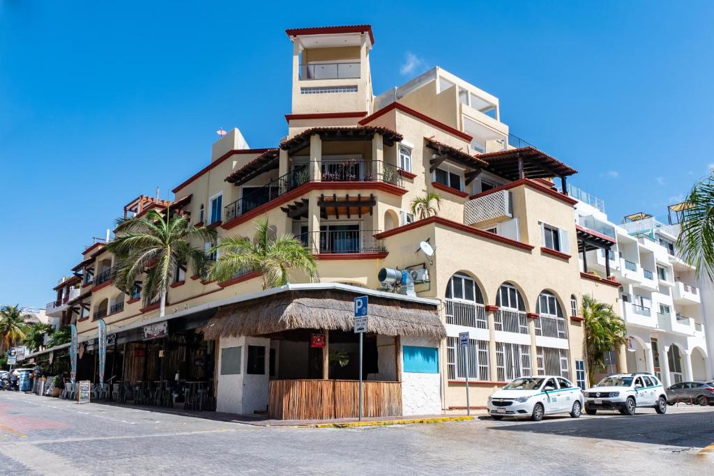 wysoki budynek z samochodami zaparkowanymi przed nim w obiekcie Magic Paradise by BVR w mieście Playa del Carmen