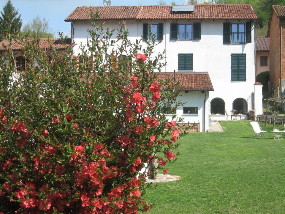a house with a bush with red flowers in the yard at beppe country house in Asti