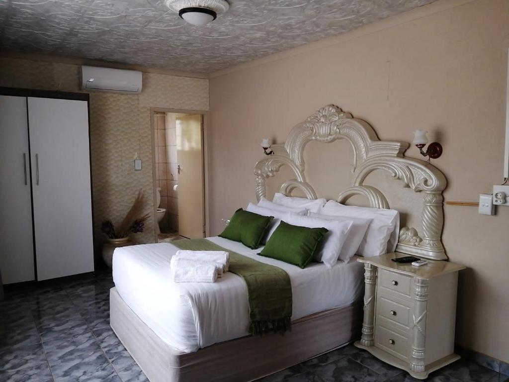 a bedroom with a large white bed with green pillows at Makhadzi's clouds lodge in Dalmada AH