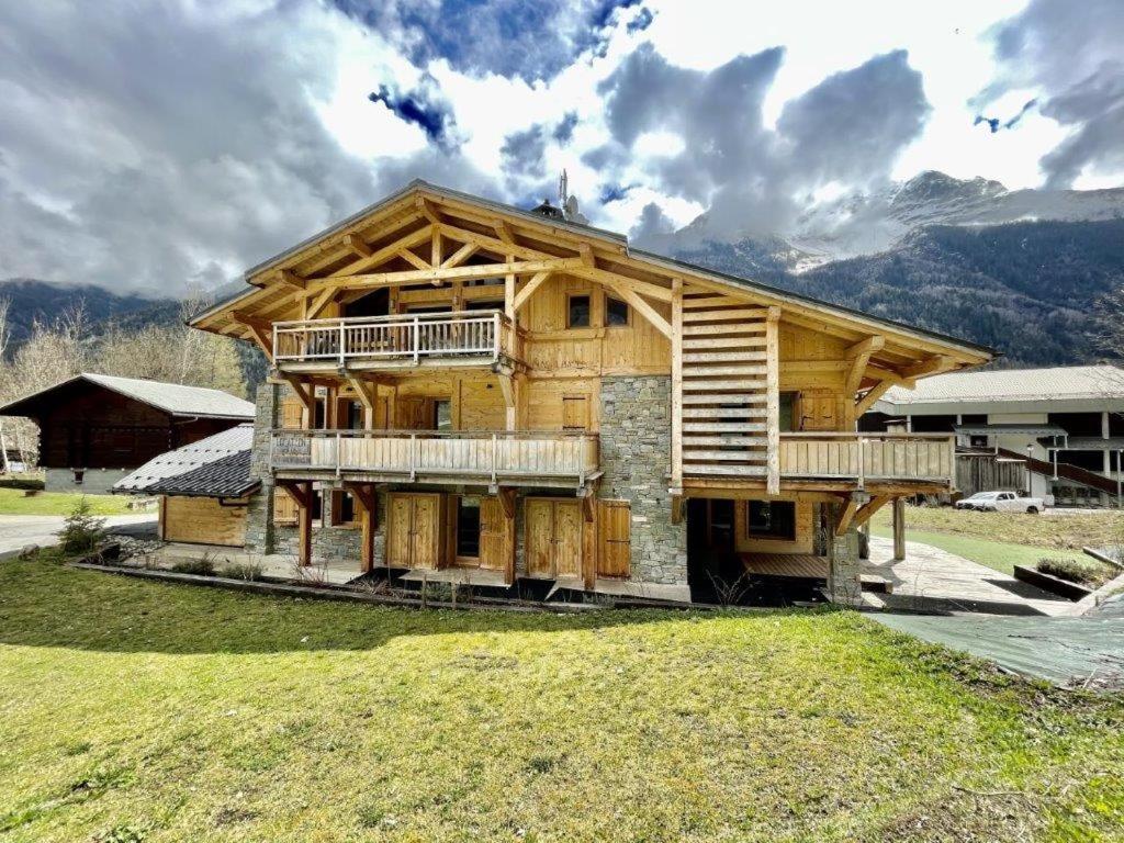 a large wooden house with two decks on a field at Chalet Caméline in Les Contamines-Montjoie