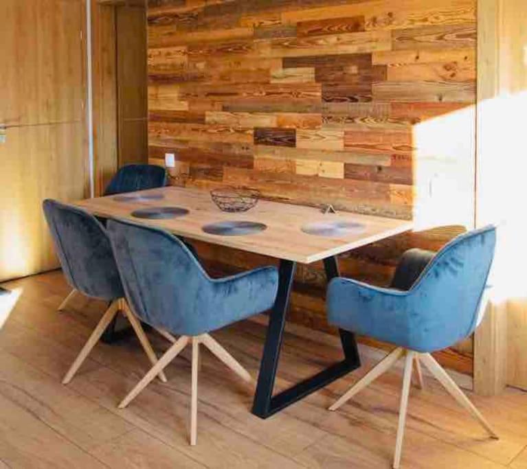 uma mesa de madeira com cadeiras azuis em frente a uma parede de madeira em 5 Dream Apartment 5 cu Parcare Privata em Oradea