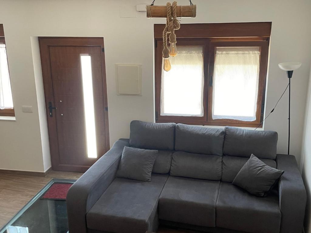 a living room with a couch and two windows at Casa Capricho in Horcajo de las Torres
