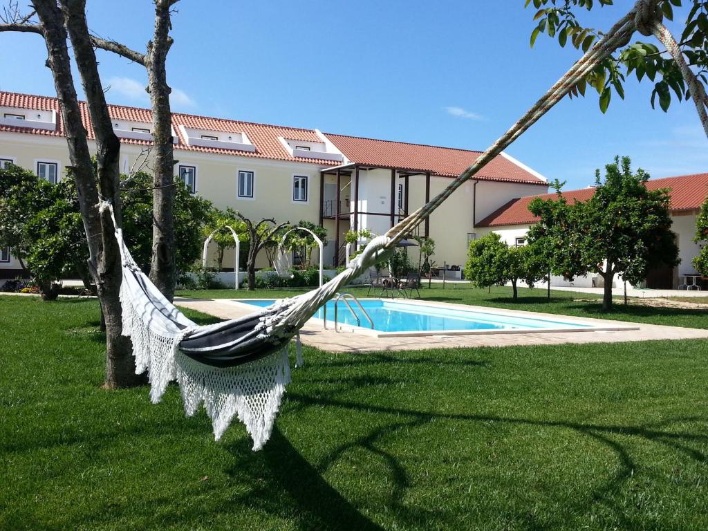 una hamaca colgada de los árboles en un patio con piscina en Casas da Moagem, en São Domingos