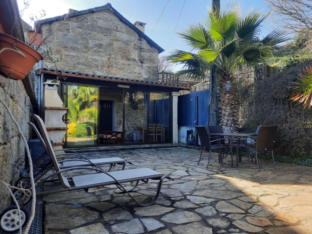 Casa Rural Cabo de Aráns في Oroso: فناء فيه كراسي وطاولة ومبنى