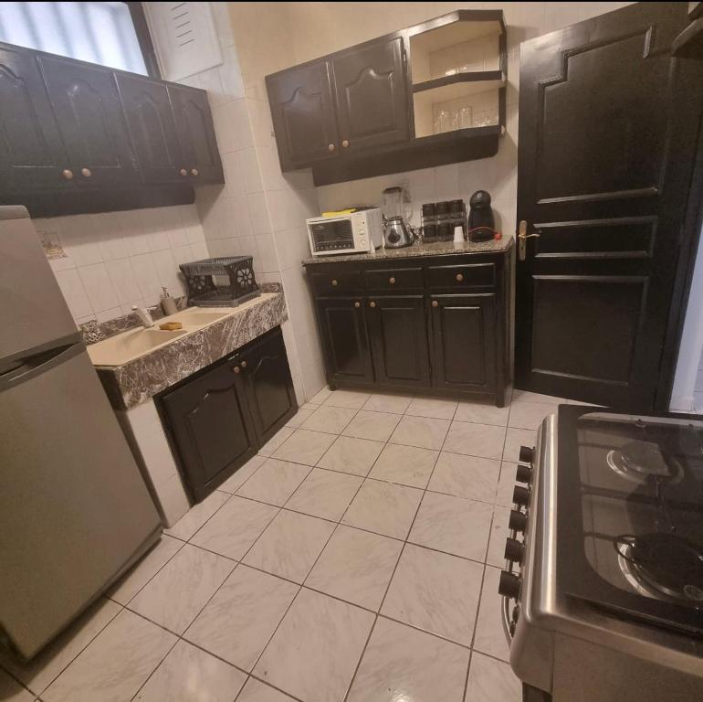 eine Küche mit schwarzen Schränken und Fliesenboden in der Unterkunft Appartement centre Agadir in Agadir