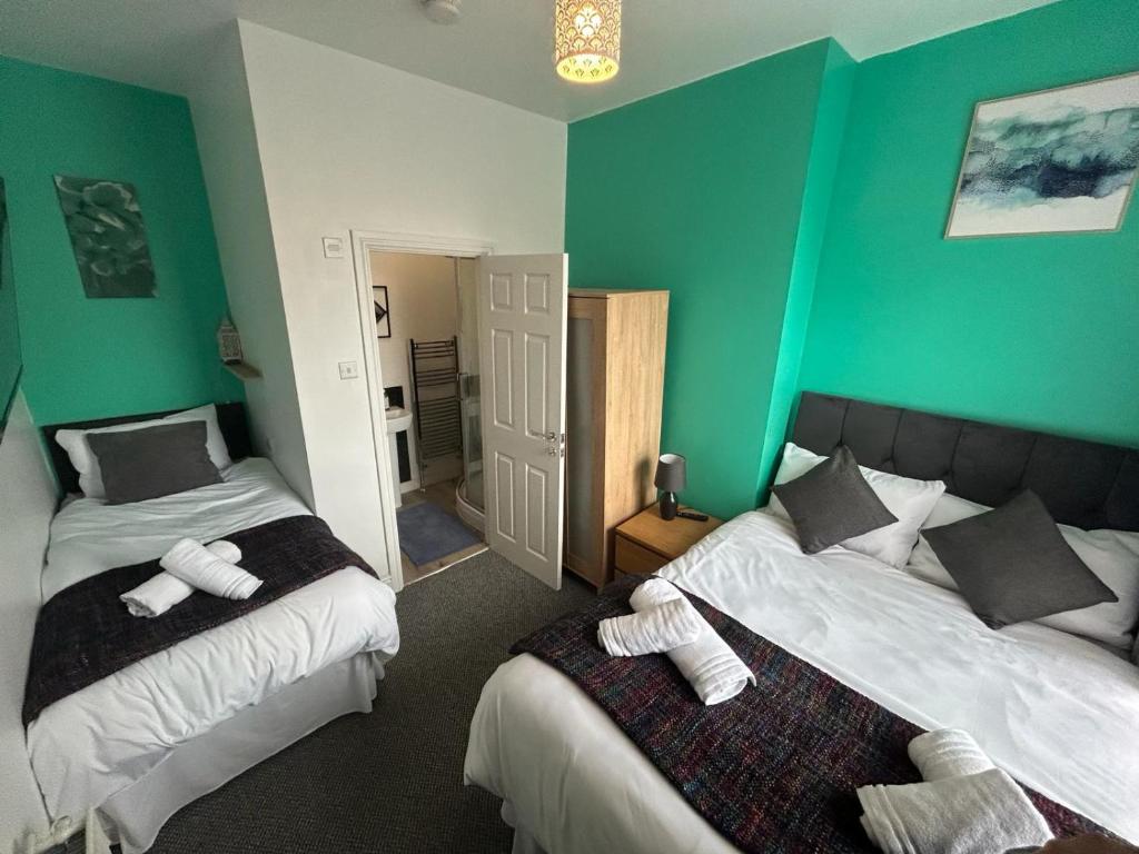 two beds in a room with green walls at West Street House in Crewe