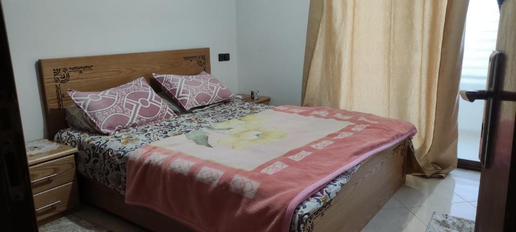 - un lit avec des draps et des oreillers roses et blancs dans l'établissement رياض النخيل, à Aïn el Apuda