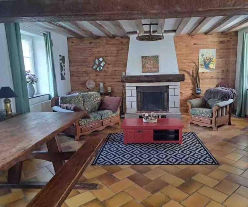 un salon avec une table et une cheminée dans l'établissement Cottage chaleureux dans un ancien corps de ferme, à Marolles
