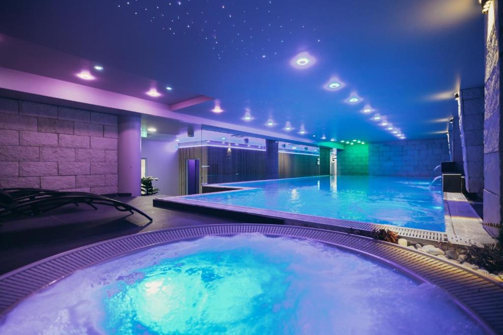 a large swimming pool in a building with a lit up tub at Wellness Spa Hotel Jola in Banja Luka
