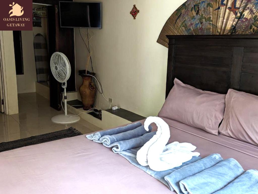a bedroom with a bed with towels and a fan at Oasis Living Getaway in Mandeville, Manchester in Mandeville