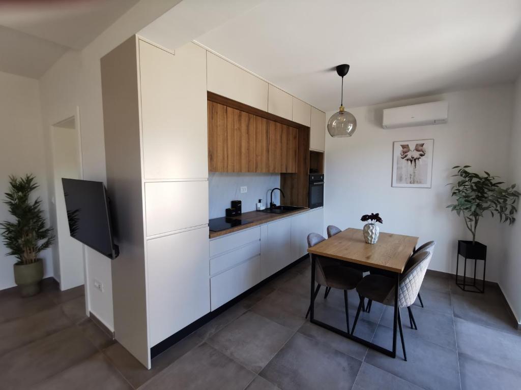a kitchen with white cabinets and a wooden table at Honoris Apartment - Brand new - Private parking - 90 m from the beach- Terrace in Slano
