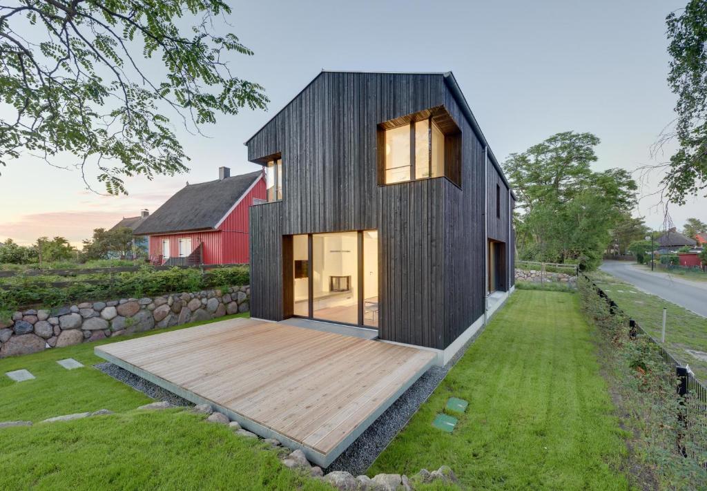 ein schwarzes Haus mit einer Terrasse und einer roten Scheune in der Unterkunft Haus Wieckin in Wieck