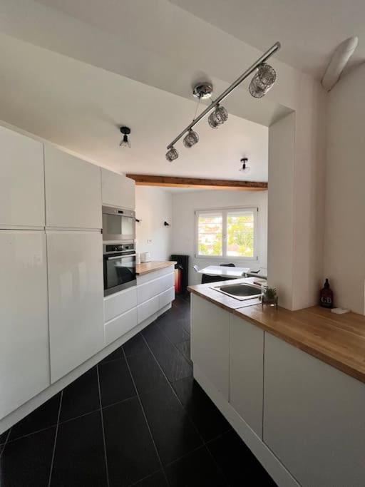 une cuisine avec des placards blancs et un sol noir dans l'établissement Le duplex du journaliste, à Besançon