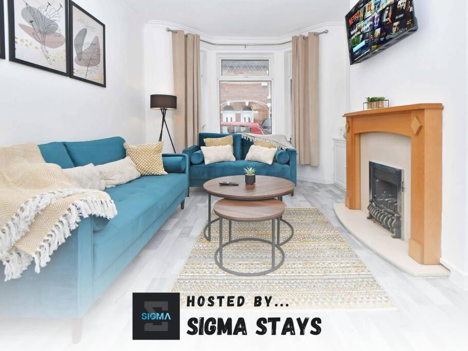 a living room with a blue couch and a table at Myrtle House - By Sigma Stays in Crewe