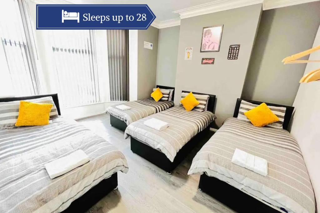 três camas num quarto com almofadas amarelas em Spacious Retreat: 8BR House in Prime Location em Liverpool