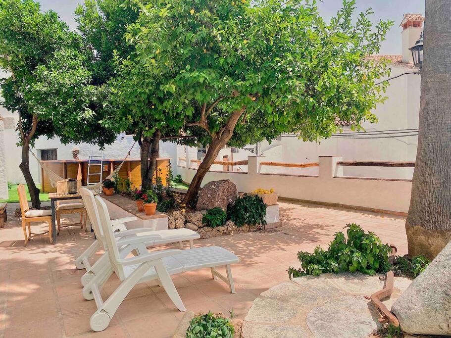 een groep witte stoelen en een tafel en een boom bij La Palmera. Casa rural con piscina privada. in Benadalid
