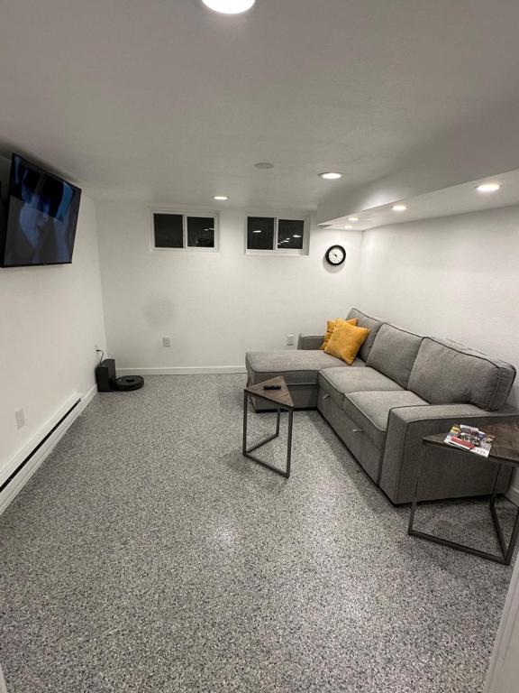 a living room with a couch and a clock on the wall at Basement Bliss: Cozy Getaway in Cheyenne