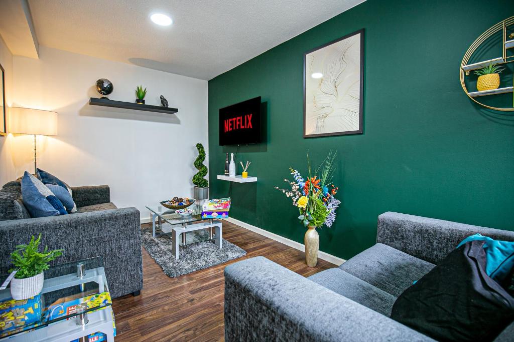 a living room with two couches and a green wall at Oldbrook House, MK City Center, Large Groups. in Milton Keynes