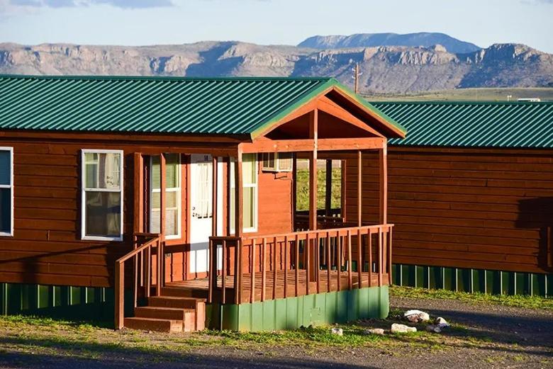 Cette maison en bois dispose d'une terrasse couverte et d'un toit verdoyant. dans l'établissement Mountain View Lodge, à Fort Davis