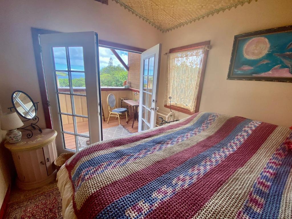 a bedroom with a bed and a view of a balcony at Artsy Cabin on Organic Farm in Naalehu