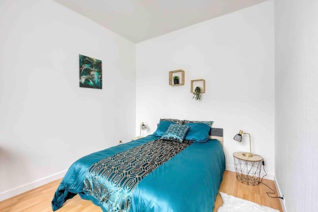 um quarto com uma cama azul num quarto branco em Paris Gentilly appartement tout équipé - RER B em Gentilly