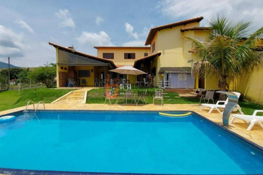a villa with a swimming pool in front of a house at Casa de Campo de frente para belas montanhas in Extrema
