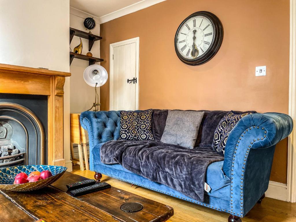 a blue couch in a living room with a clock on the wall at Victorian Refuge-City centre in Canterbury