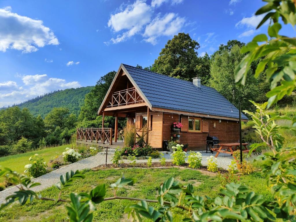 uma cabana de madeira na floresta com um jardim em Ogród Weigla em Janowice Wielkie