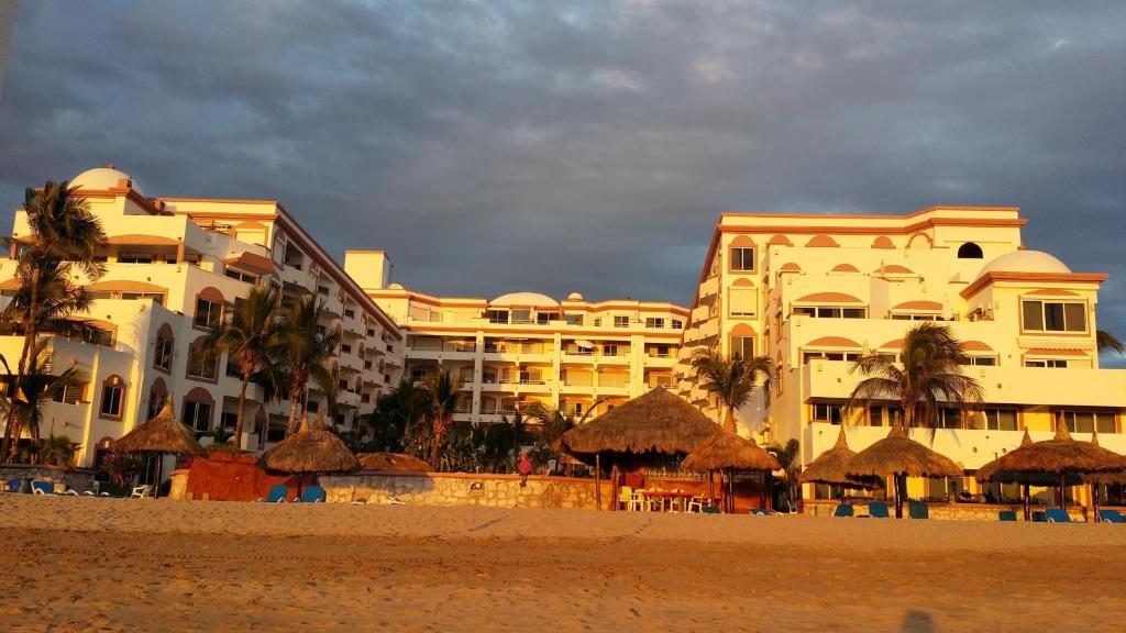 eine Gruppe von Gebäuden am Strand mit Sonnenschirmen in der Unterkunft Maz4you Beachfront Condo in Mazatlán