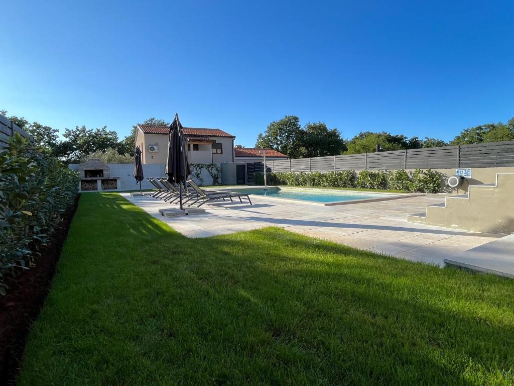 eine Liegewiese mit Sonnenschirm und Pool in der Unterkunft Casa Mia in Poreč