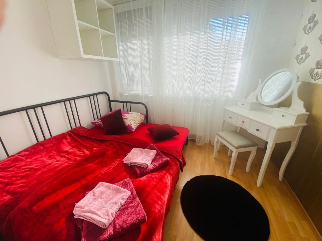 a bedroom with a red bed with a desk and a mirror at Sweet apartment in Bratislava