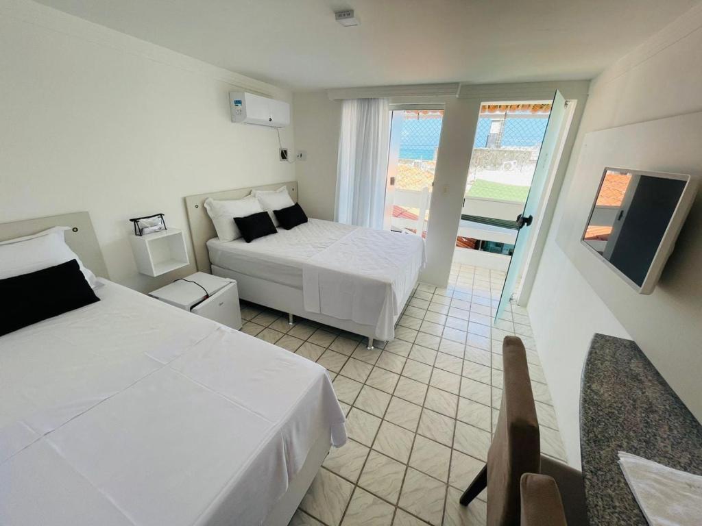 a hotel room with two beds and a balcony at Temporada In Natal - Pousada in Natal