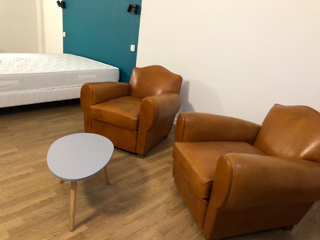 een woonkamer met 2 stoelen en een bed bij Maison proche du centre ville - Mitoyenne in Saint Die