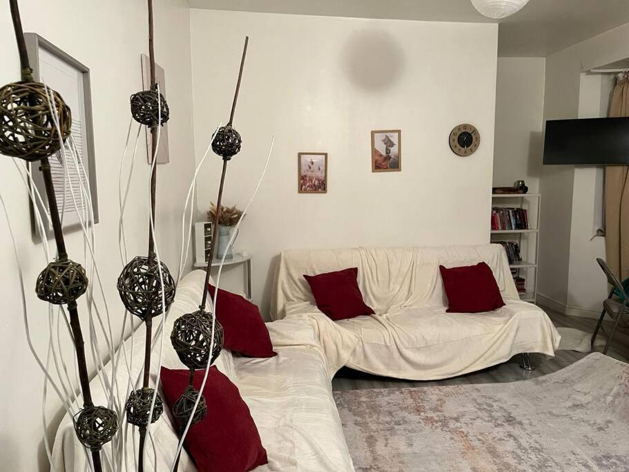 a living room with a white couch and red pillows at Cosy two bedroom flat in London