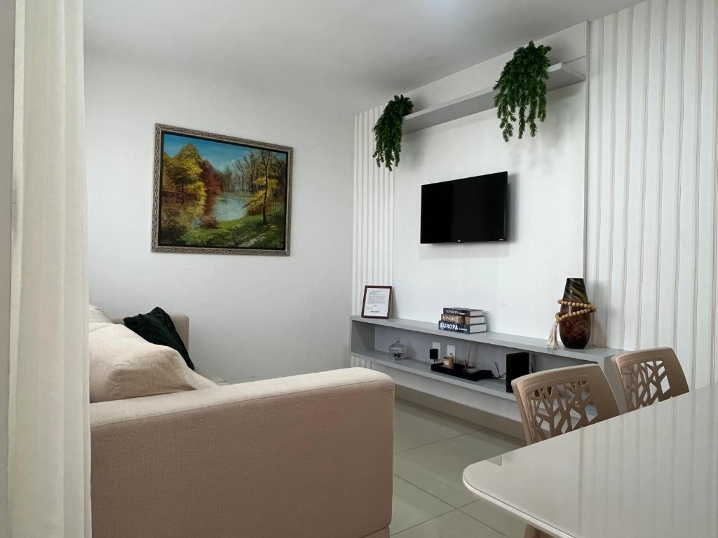 a living room with a couch and a tv on a wall at Casa em PontaNegra Aconchegante in Natal