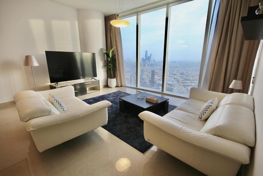 - un salon avec deux chaises blanches et une télévision dans l'établissement private Suite by Golden Hospitality 98, à Riyad