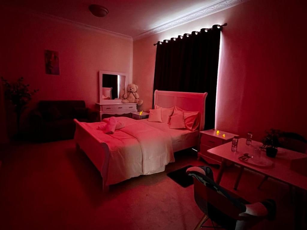 ein rotes Schlafzimmer mit einem Bett, einem Schreibtisch und einem Tisch von sidx sidx sidx in der Unterkunft Retreat Haven in al-Ain