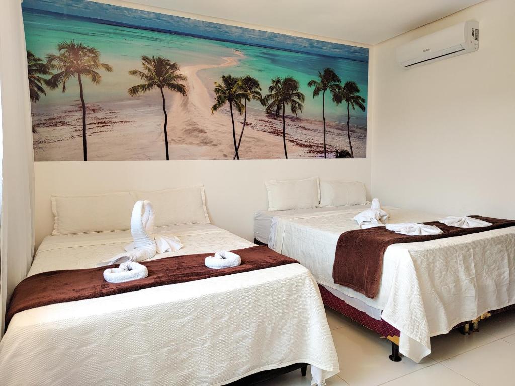 two beds in a room with a painting on the wall at Encantos de Maragogi in Maragogi