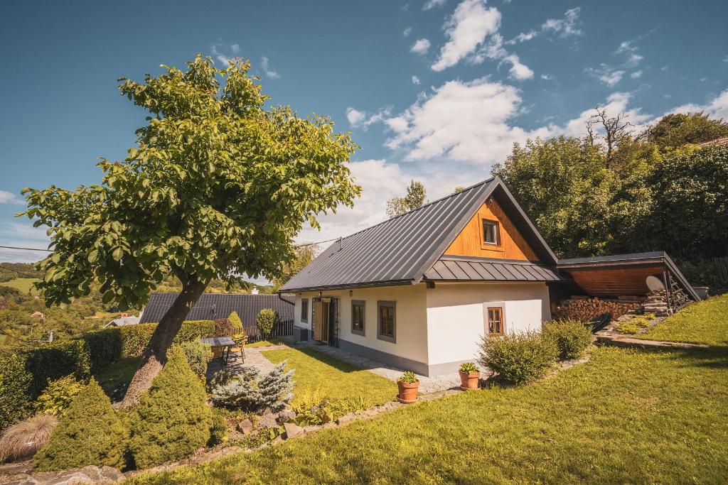une petite maison blanche avec un toit noir dans l'établissement .. chalupa na slnečnom kopci .., à Banská Štiavnica