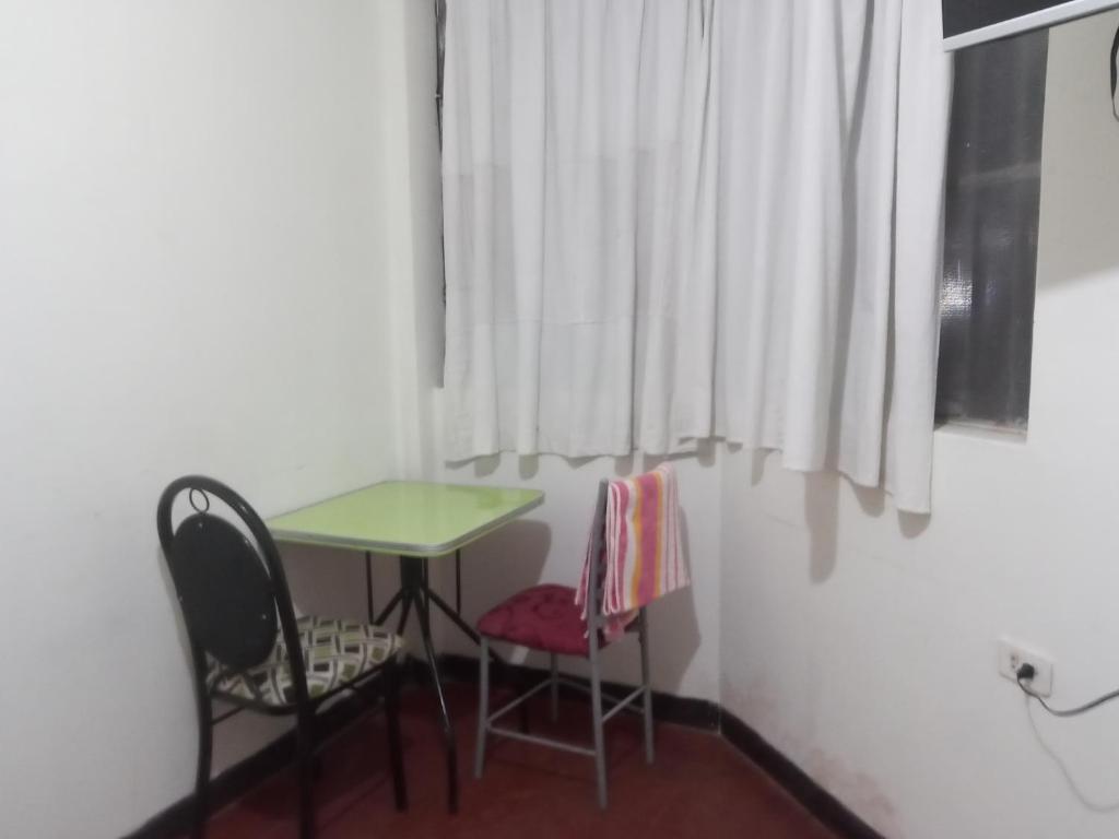 una mesa pequeña y 2 sillas en una habitación con ventana en Hospedaje BERTHITA en Chiclayo